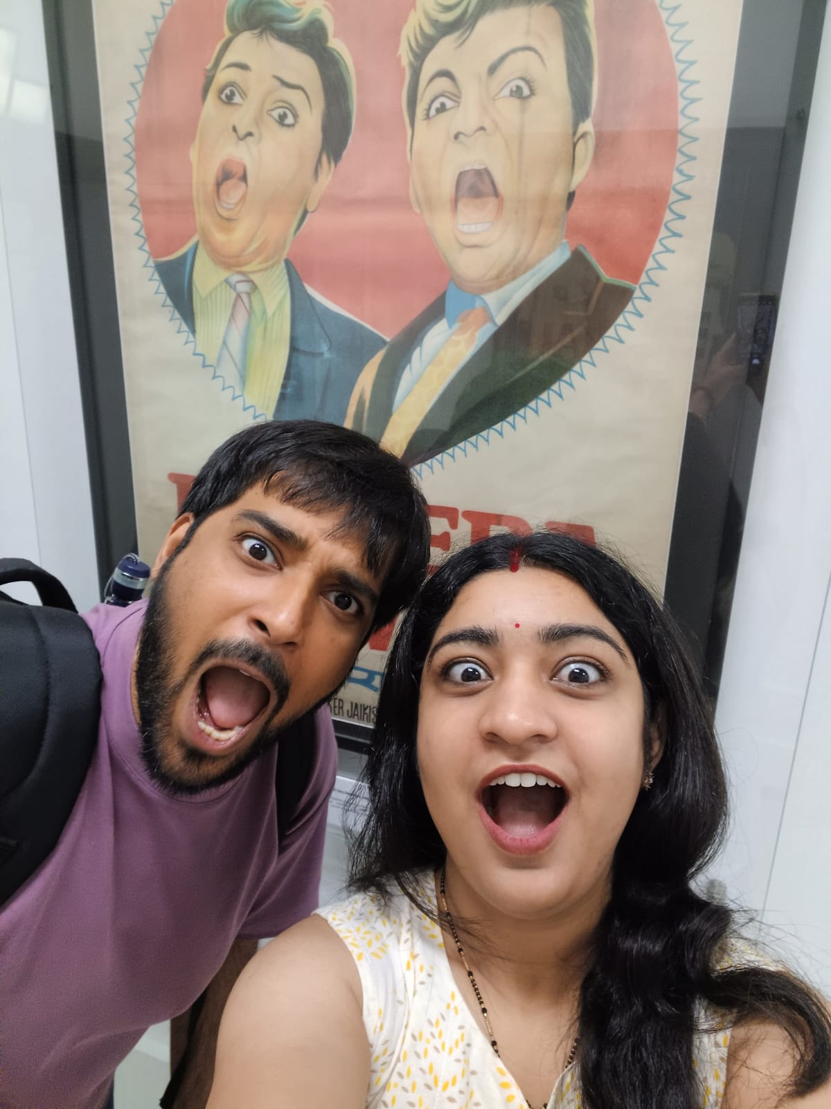 Jahnavi and Kartikeya copying the shocked faces on the movie poster behind them